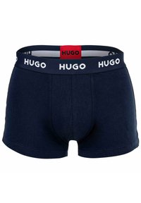 Marineblaue Boxershorts aus Baumwolle, mit einem weißen Markenbund und einem roten Etikett. Glatte Textur und körpernahe Passform mit kurzen Beinen.