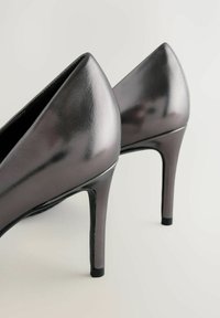 Fényes szürke magassarkú cipők hegyes orral, sima felülettel és fekete gumitalppal.