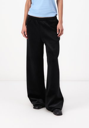 Pantaloni neri a gamba larga realizzati in tessuto morbido, dotati di una vita elastica per il comfort e una vestibilità rilassata.