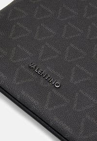 Black leather clutch featuring a textured surface with a repeating Valentino logo pattern. Black metal logo accent prominently displayed.