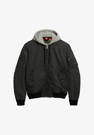 Chaqueta bomber para hombre en tela negra con capucha gris. Cuenta con cierre de cremallera frontal, bolsillos laterales y un bolsillo en la manga con detalles de costura.