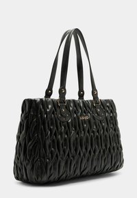 Borsa a tracolla nera trapuntata con texture in pelle liscia, hardware in tono oro, doppio manico e dettaglio logo embossato sulla parte anteriore.