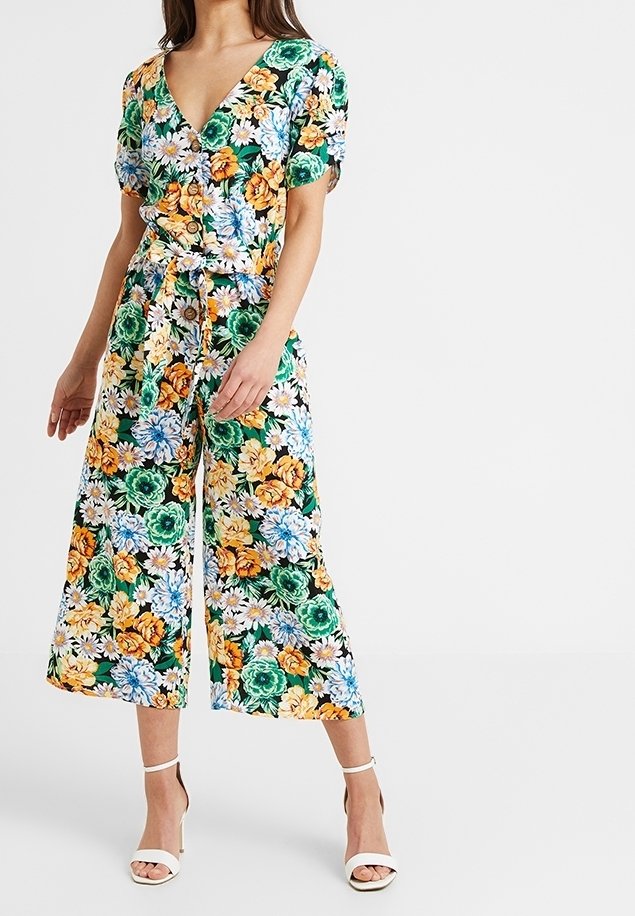 Kwiatowy kombinezon z dekoltem w kształcie litery V, krótkimi rękawami i paskiem w talii. Charakteryzuje się odważnym połączeniem pomarańczowych, zielonych i niebieskich kwiatów na czarnym tle.