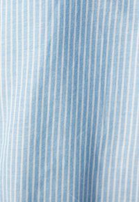 Tessuto azzurro chiaro con sottili strisce bianche, superficie leggermente strutturata, adatto per capi d'abbigliamento o arredi morbidi.