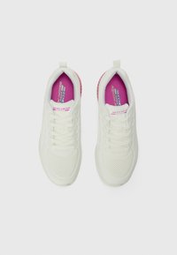Baskets blanches en matériau synthétique lisse et en mesh, avec des accents roses sur le talon et le logo, ainsi qu'une semelle texturée.