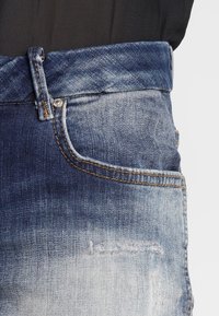 Shorts in denim con un design blu sbiadito, stile a cinque tasche, orlo sfrangiato e cuciture a contrasto lungo la vita e le tasche.