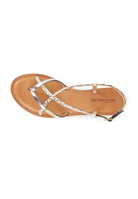 Sandalo in pelle marrone con cinturini intrecciati argento e bianco. Presenta una suola piatta con dettagli cuciti e un logo sulla soletta.