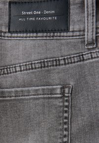 Tela de denim gris con una textura suave, un patrón sutil y una etiqueta de cuero negro con "Street One - Denim" y "TODOS TIEMPOS FAVORITO".