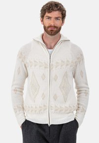 Pull à fermeture éclair en maille couleur crème avec motifs géométriques légers, doté d'un col montant et de poignets côtelés. Confectionné dans un tissu doux et texturé.