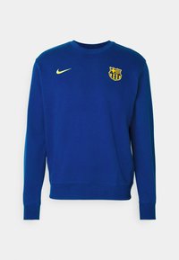 Sudadera azul hecha de mezcla de algodón con mangas largas, cuello redondo, logo amarillo de Nike y emblema de Barcelona en el pecho.