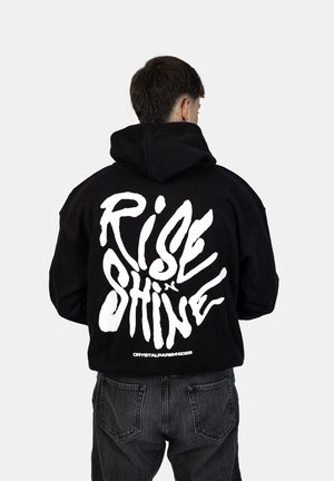 Felpa nera con cappuccio caratterizzata da una grande scritta bianca stampata "RISE & SHINE" sul retro. Il design ha una vestibilità ampia e una tasca a marsupio.