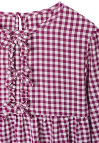 Violett-weiße Karo-Muster-Bluse mit runder Halslinie, Rüschendetails und Knopfverschluss auf der Rückseite. Weiches Gewebe.