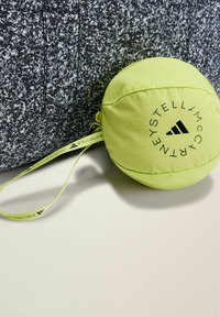 Black-and-white speckled backpack with a bright yellow drawstring pouch featuring a logo and a strap for easy carrying.