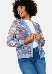 Ziedu bomber jaka zila krāsā ar vieglu, caurspīdīgu audumu. Iespējas: rozā un baltie ziedu raksti, ribotie piedurkņu gali un cieta josta.