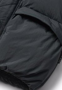 Czarna, pikowana kurtka puchowa o gładkiej fakturze. Posiada złożony mankiet i elastyczny dół dla dopasowanego wyglądu. Minimalistyczny design bez widocznych elementów metalowych.