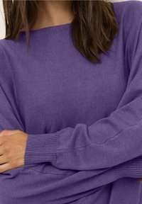 Lila långärmad tröja med avslappnad passform, ribbade ärmmuddar och mjuk textur. Har en vid halsringning och slät tygfinish.