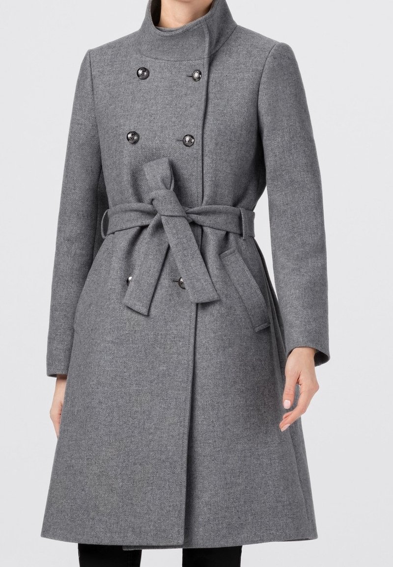 Grå kappa i ullblandning med hög krage, dubbelknäppt design, stora knappar och ett tygbälte i midjan. Slät textur, knälång.