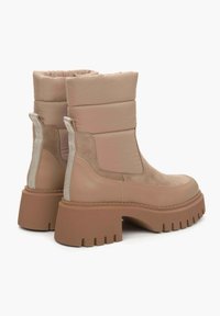 Beige enkellaarsjes met padding, gemaakt van glad leer en suède accenten, met een chunky rubberen zool en een trekband aan de achterkant.