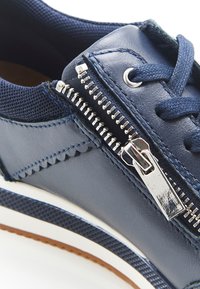 Marineblauwe sneaker van leer en mesh, met een zijrits, geprofileerde accenten en een witte rubbere zool.