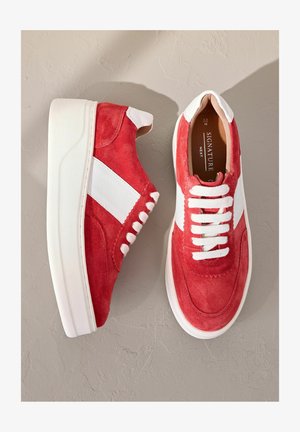 Sneakers in suede rosso con dettagli e lacci in pelle bianca. Presentano una suola bianca spessa e un design con striscia laterale. Stile casual e sportivo.