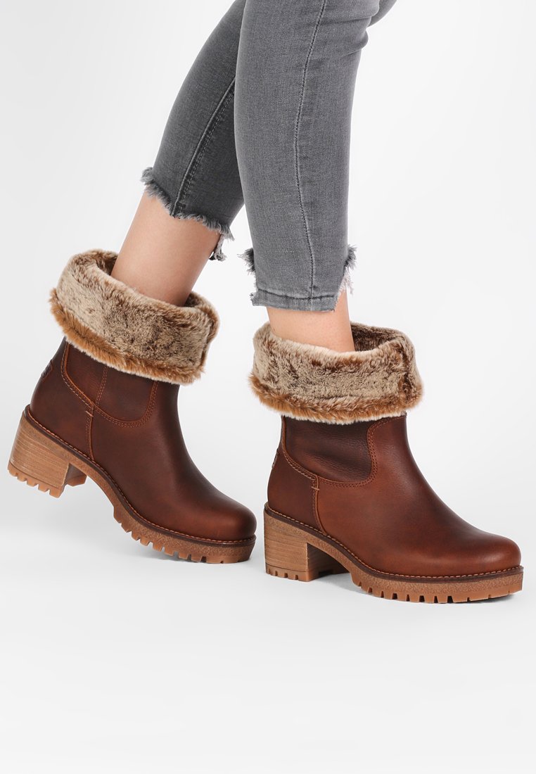 Botas de tobillo de cuero marrón con un puño de piel sintética, tacón de madera apilada y suela de goma texturizada, con punta redonda y costuras laterales.