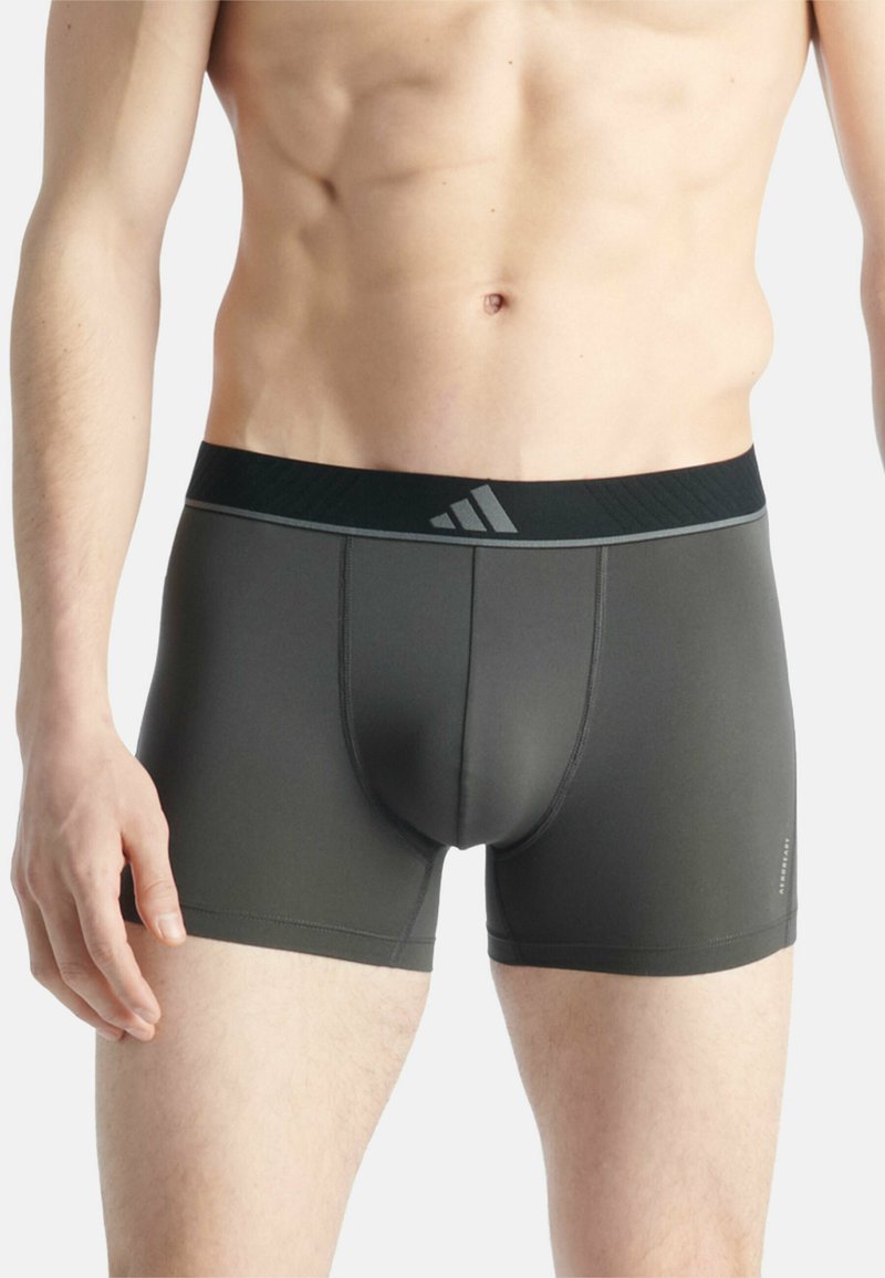 Boxers gris pour homme avec une taille élastique noire ornée d'un logo. Le matériau semble lisse et ajusté, adapté à une utilisation athlétique.