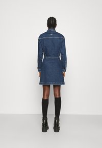 Denimhemdkleid mit langen Ärmeln, tailliertem Bund und knielangem Saum. Dunkelblaue Farbe mit Steppdetails und Kragen.
