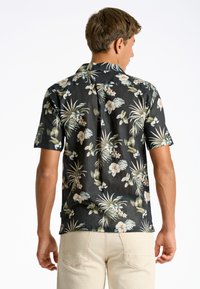 Camicia a maniche corte in tessuto nero. Presenta modelli tropicali bianchi e verdi con una vestibilità comoda e colletto classico.