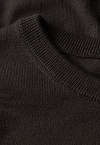 Dunkelbrauner Strickpullover mit einem gerippten Rundhalsausschnitt. Die Textur wirkt weich und glatt, mit einem gleichmäßigen Muster über den Stoff.