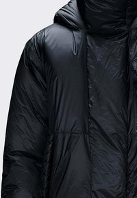 Giacca imbottita nera con cappuccio, caratterizzata da un design trapuntato e una texture liscia. Chiusura con cerniera e dettagli di cuciture visibili.