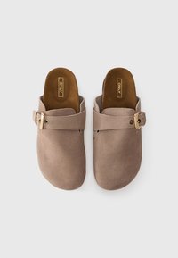 Beige semskede slip-on mules med avrundet tå, lærrem og gullspenne. Myk tekstur med polstret såle.