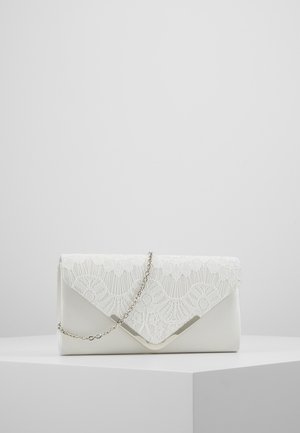 Weiße Clutch mit Spitzenklappe, silbernem Rand und zartem Silberkettenriemen, präsentiert auf einem weißen geometrischen Podest vor schlichtem Hintergrund.