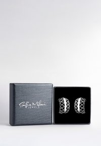 Silvriga örhängen med geometrisk design, presenterade i en svart sammetfodrad låda, med en strukturerad blå utsida och ett märkeslogotyp.