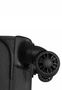 Esquina de una maleta de tela negra con ruedas dobles de plástico negro que presentan un diseño detallado de múltiples radios y una unión suave para una fácil maniobrabilidad.