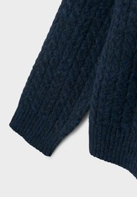 Manga de suéter de punto en navy con un patrón de cable texturizado y puño acanalado. La tela parece gruesa y suave, mostrando un diseño acogedor.