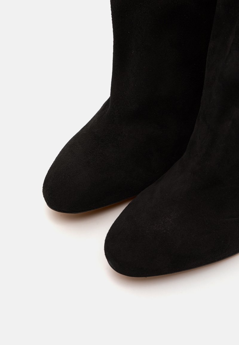 Black suede ankle boots with a pointed toe design, smooth texture, and minimalistic look, suitable for various occasions.