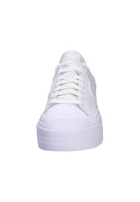 Białe trampki z gładką syntetyczną cholewką, okrągłym noskiem i płaską gumową podeszwą. Posiadają sznurowaną konstrukcję oraz wytłoczone logo na języku.