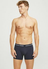 Boxer-briefs bleu foncé avec une ceinture élastique noire portant la mention "JACK & JONES" en texte blanc. Fabriqués en tissu doux et extensible.