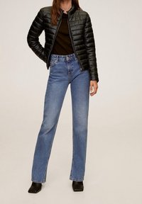 Sort pufferjakke med ribbet tekstur, parret med højtaljede blå denim straight-leg jeans og ankelstøvler.