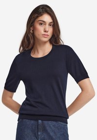 Marinblå kortärmad tröja i mjukt stickat material, med rund halsringning och ribbade ärmslut och nederkant. Slät textur med en figurnära silhuett.