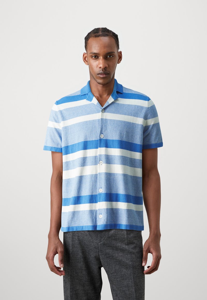 Camicia a maniche corte con bottoni di colore azzurro chiaro, decorata con strisce orizzontali blu scuro e bianche. Presenta un colletto dritto e una vestibilità rilassata.