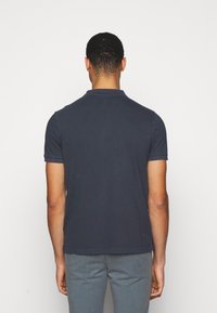 Polo shirt bleu marine à manches courtes avec col, présentant un design uni et une coupe ajustée, fabriqué en tissu coton doux.