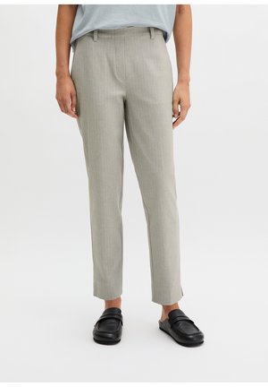 Jasnoszare, dopasowane spodnie o długości do kostek, noszone z czarnymi wsuwanymi mokasynami i jasnoniebieskim, włożonym do środka topem.