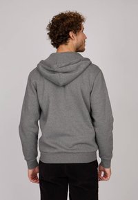 Sweatshirt gris en tissu doux, avec une capuche à cordon, des poignets et un ourlet côtelés, un design minimaliste et une coupe décontractée.