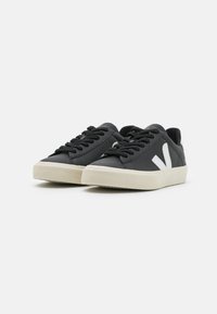 Sneaker in pelle nera con accenti bianchi, lacci piatti, suola in gomma testurizzata e punta rotonda. Design minimalista, adatte per un abbigliamento casual.
