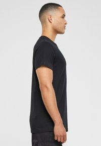 Black short-sleeve T-shirt, made of smooth fabric, features a classic crew neckline and a straight fit, shown from the side.