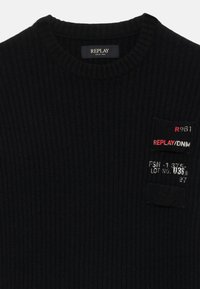Pulover negru cu dungi, având un guler rotund. Detalii notabile includ un patch în față cu numele brandului și elemente numerice. Textură moale.