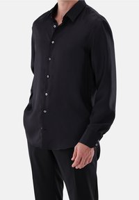 Zwarte longsleeve shirt van gladde stof, met een klassieke kraag, knoopsluiting en knoopmanchetten. Elegante en verfijnde uitstraling.
