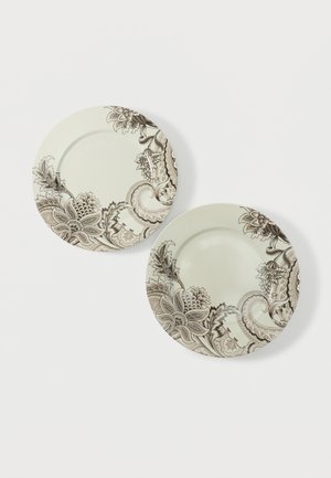 Deux assiettes rondes crème ornées de motifs floraux et cachemire bruns complexes le long des bords sur un fond blanc.