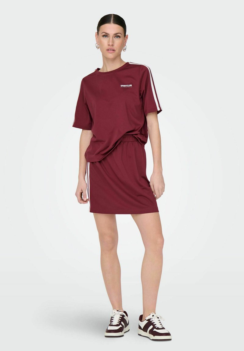 Bordeaux katoenmengseloutfit met een losse T-shirt en een rok met elastische taille, voorzien van witte zijkanten en een klein logo-detail.